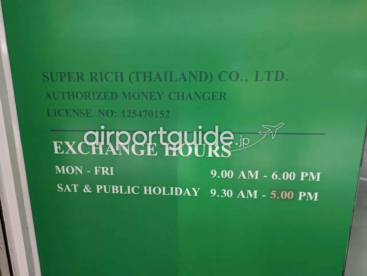 Super Rich (Thailand) 両替店の営業時間案内板。緑地に白と黒の英字で『SUPER RICH (THAILAND) CO., LTD. AUTHORIZED MONEY CHANGER LICENSE NO: 125470152』『EXCHANGE HOURS MON-FRI 9.00 AM - 6.00 PM／SAT & PUBLIC HOLIDAY 9.30 AM - 5.00 PM』と記載。