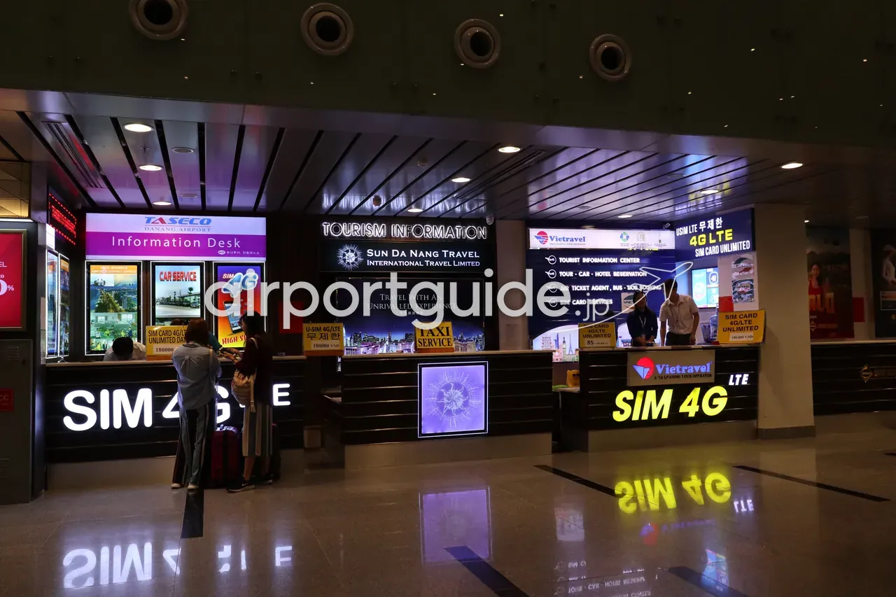 ダナン国際空港到着ロビーの各種サービスカウンター。「TASECO Da Nang Airport Information Desk（案内所）」「Tourism Information／Sun Da Nang Travel」「Vietravel Tourist Information Center（ツアー・車・ホテル予約、SIMカード）」「TAXI SERVICE」「SIM 4G LTE」のブースが並ぶ。