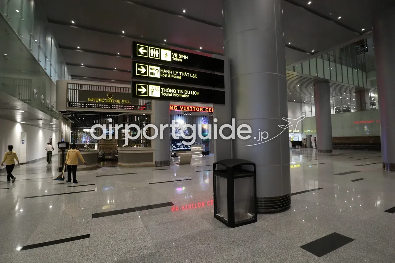 ダナン国際空港到着ホールの吊り下げ案内サイン。「VỆ SINH／Toilets（トイレ）」「HÀNH LÝ THẤT LẠC／Lost & Found（遺失物）」「THÔNG TIN DU LỊCH／Tourist Information（観光案内）」の矢印。奥にインターコンチネンタルのラウンジと Da Nang Visitor Center。
