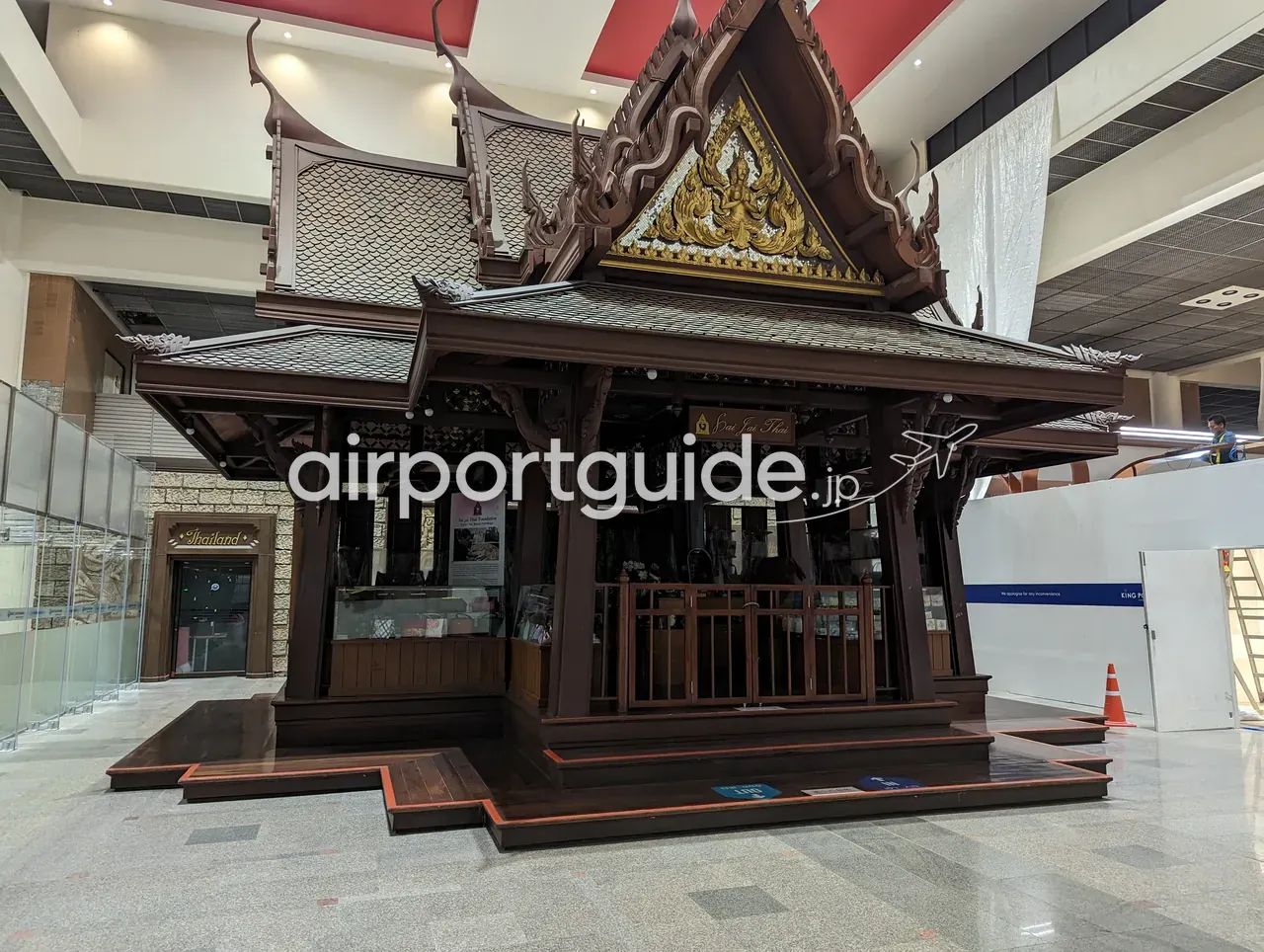ドンムアン空港内の土産物店「Sai Jai Thai」。タイ様式の木造楼閣（サラ）を模した濃い木目の建屋で、屋根に金色の破風装飾、隣に「Thailand」の店とKing Powerの仕切り壁がある。