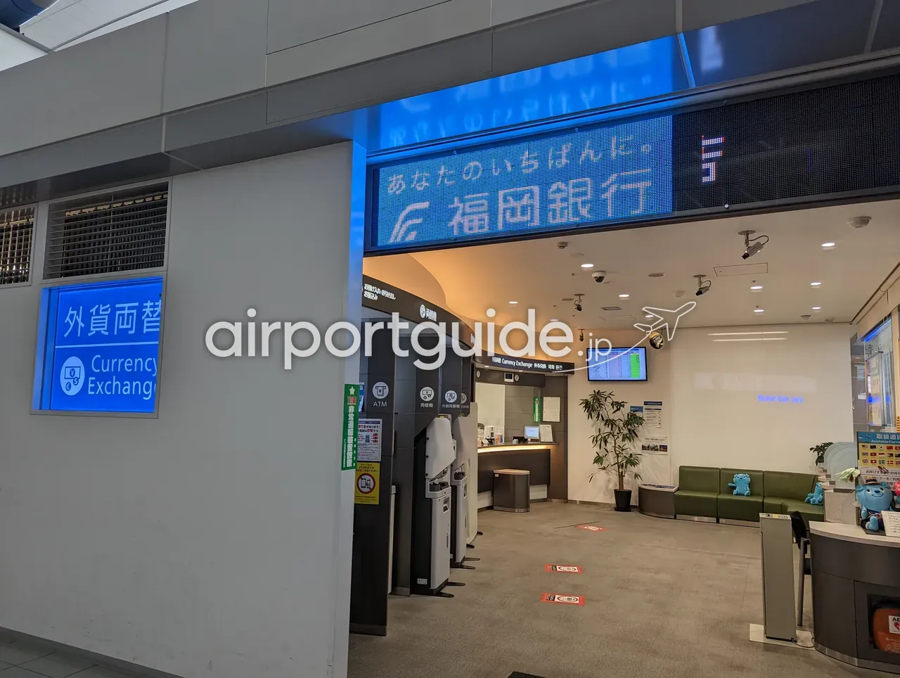 福岡銀行の外貨両替コーナー。両替機やATMが並び、奥に有人カウンターとレート表示板がある。