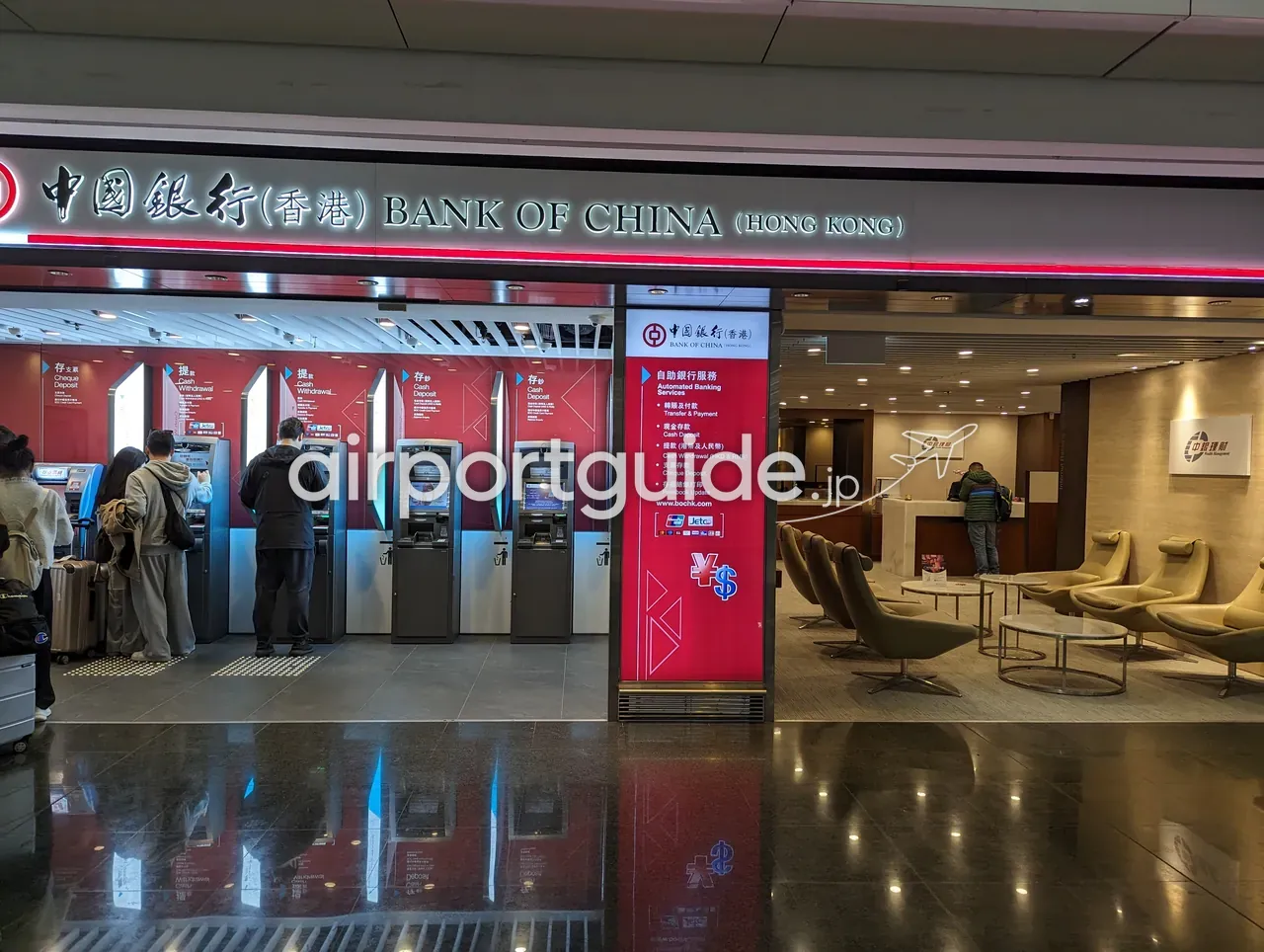 香港国際空港の中国銀行（香港）のATMコーナーと支店。複数のATMを利用する人、右手に応接ソファ。『BANK OF CHINA (HONG KONG)』の看板。
