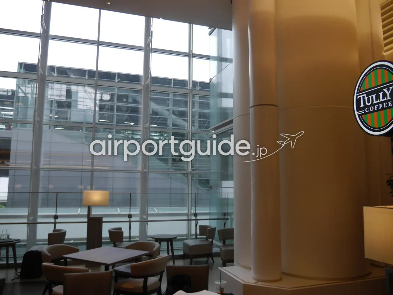 羽田空港内のタリーズコーヒーの座席スペース。大きなガラス壁沿いにテーブルと椅子が並ぶ、明るく空いた店内。