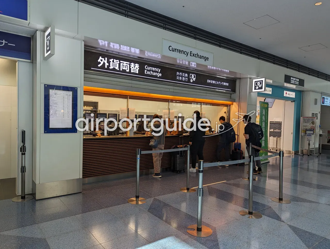 羽田空港の外貨両替カウンター（日本空港ビルデング直営店）。数人の利用客がカウンターで両替の手続きをしている。