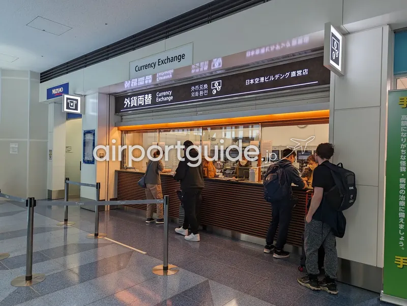 羽田空港の外貨両替カウンターで両替する利用客たち。すぐ隣に銀行のATMコーナーがある。