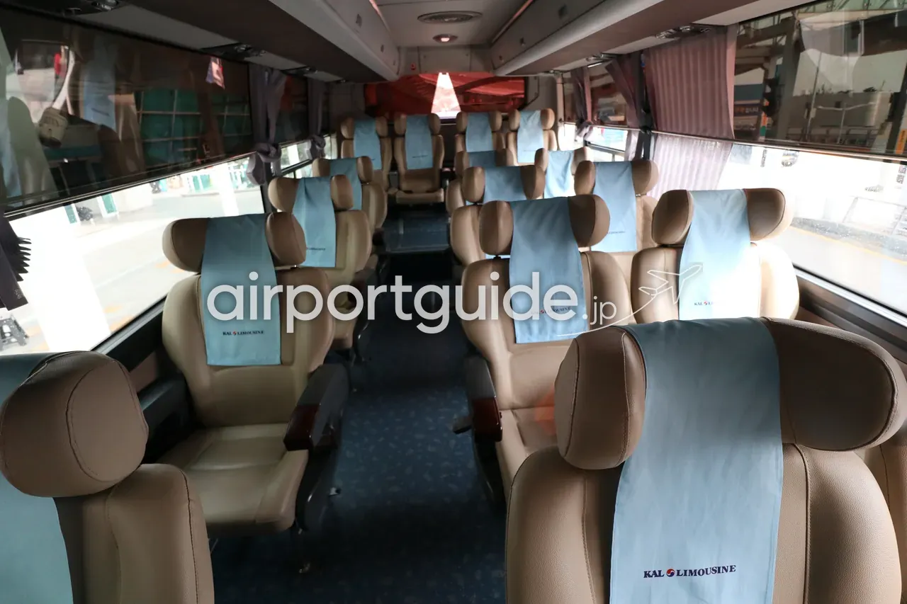 空港リムジンバス（KAL LIMOUSINE）の車内。ベージュの革張り座席に「KAL LIMOUSINE」のロゴ入りカバーがかけられ、整然と並ぶ。