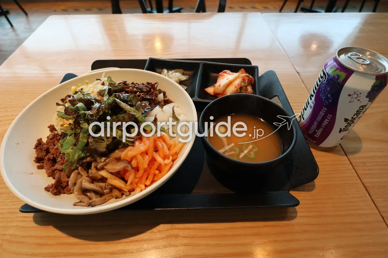 空港のフードコートで提供されたビビンバの定食トレー。スープ、キムチ、ぶどうジュース（Tropicana）が添えられている。