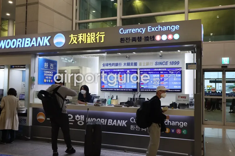 仁川空港のウリ銀行の外貨両替カウンター。スタッフと、バックパックやスーツケースの旅行者数人が窓口の周りにいる。