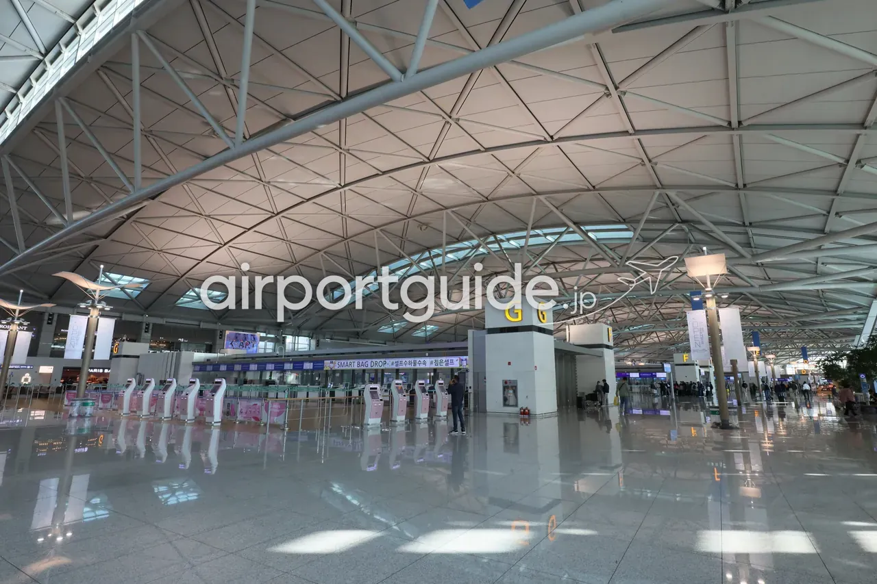 仁川空港のセルフバッグドロップ・エリア。「SMART BAG DROP 셀프수하물수속」の横断幕の下、ピンク色のセルフ機が並ぶガランとした出発ホール。
