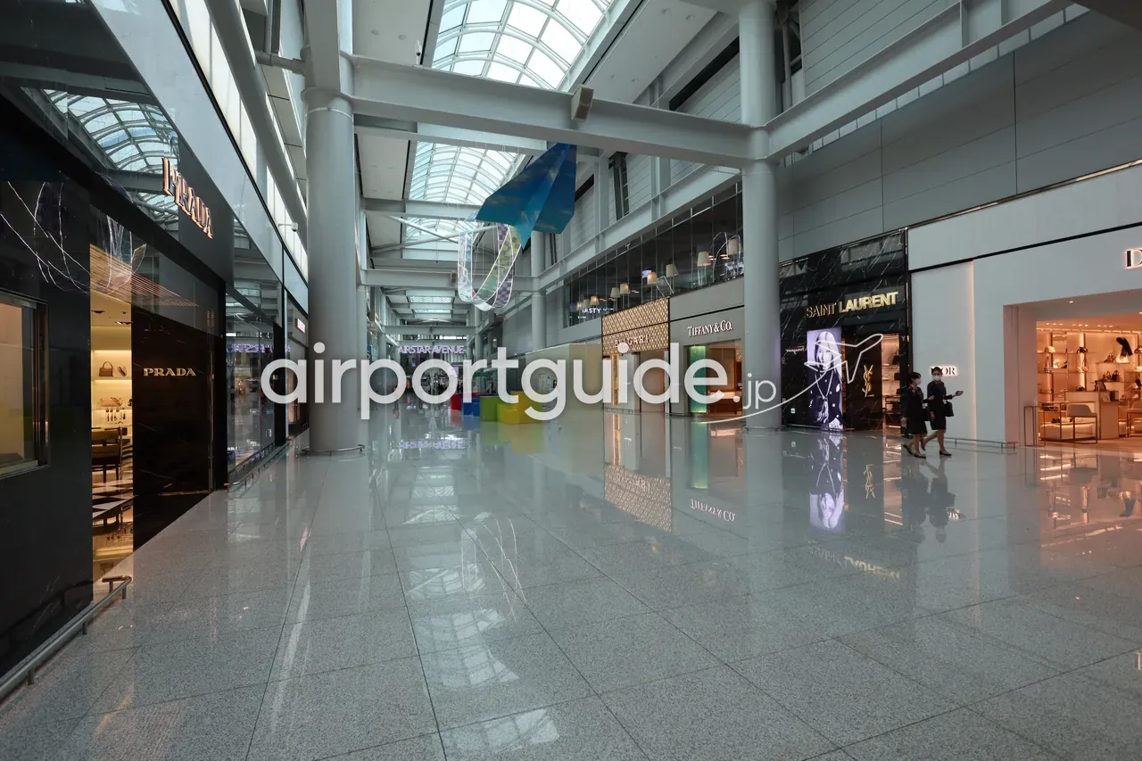 仁川空港の制限エリアの高級ブランド街「STAR AVENUE」。PRADA、Tiffany & Co.、BVLGARI、SAINT LAURENT、Diorなどの路面店がガラス屋根の通路沿いに並ぶ。