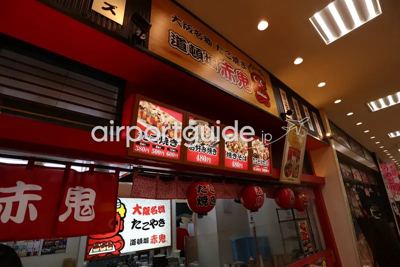 道頓堀 赤鬼の店頭。たこ焼きにお好み焼き、大阪の看板メニューが並ぶ。