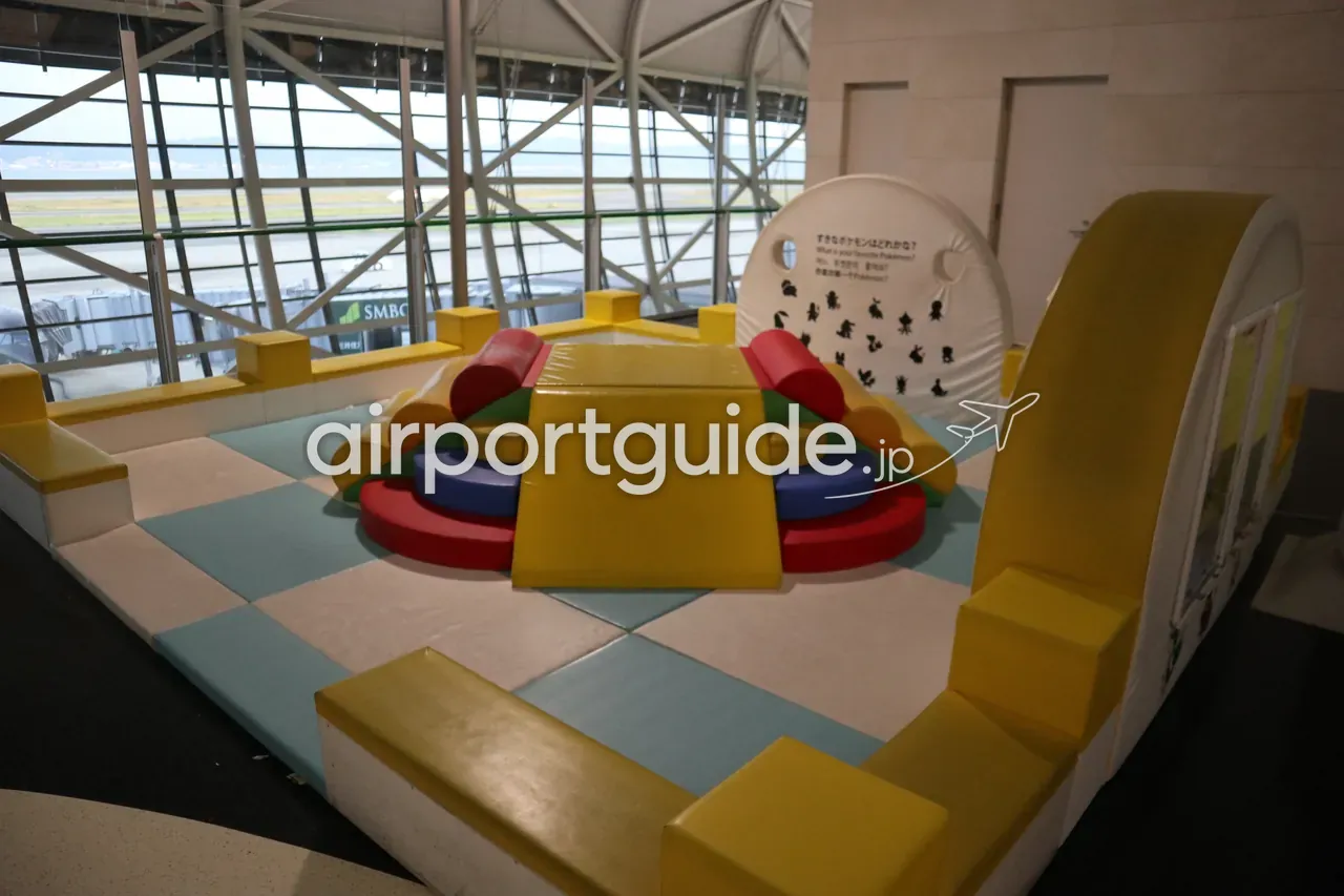 関西空港の搭乗待合エリアにあるポケモンをテーマにした子ども向けプレイスペース。カラフルなソフト遊具、大きな窓の外に滑走路と海。
