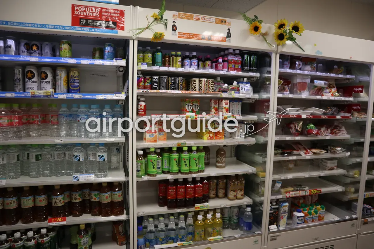 関西空港内コンビニの飲料コーナー。ビール・お茶・水などが冷蔵ショーケースにぎっしり並び、上に「POPULAR SOUVENIRS」の案内。
