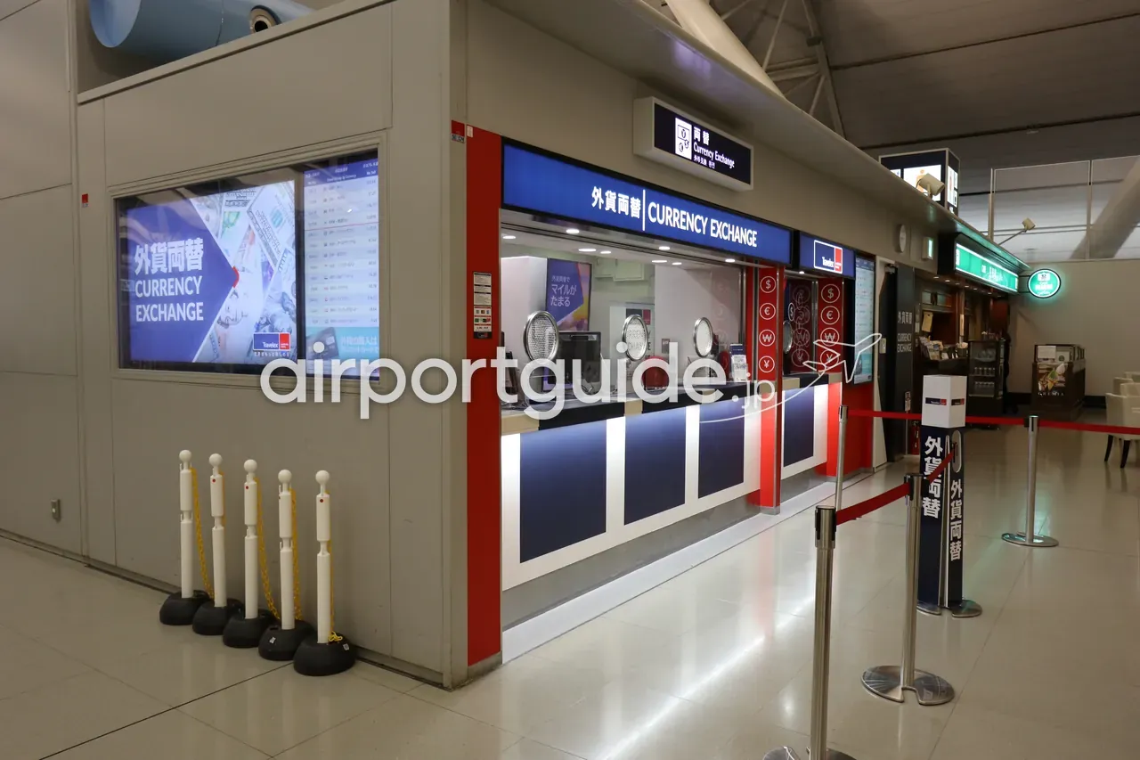 関西空港の外貨両替（CURRENCY EXCHANGE）カウンター。窓口の上に「両替 Currency Exchange」のサイン、左に為替レートのデジタル表示ボード。