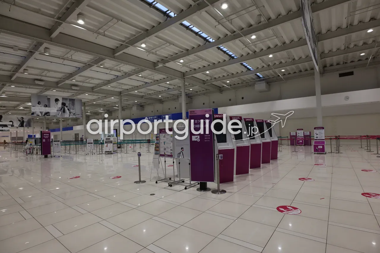 関西空港第2ターミナルのチェックインエリア。「チェックイン CHECK-IN」「保安検査場 Security Check」「国内線 出発口」の案内サインとPeachのカウンター。