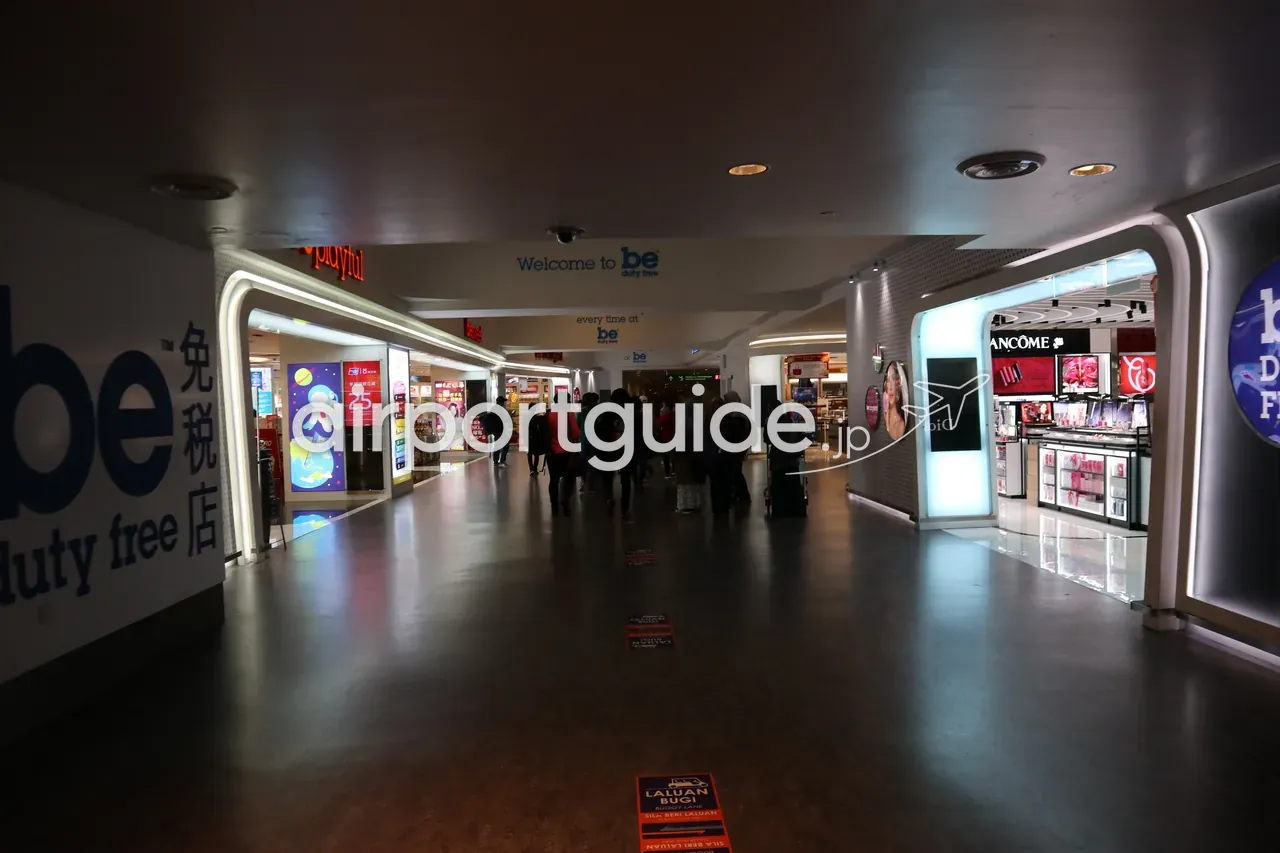 KLIAターミナル2制限エリアの免税店「be duty free」の通路。「Welcome to be duty free / be 免税店」のサインの下に、DiorやLancômeの化粧品ブランド店が並ぶ。