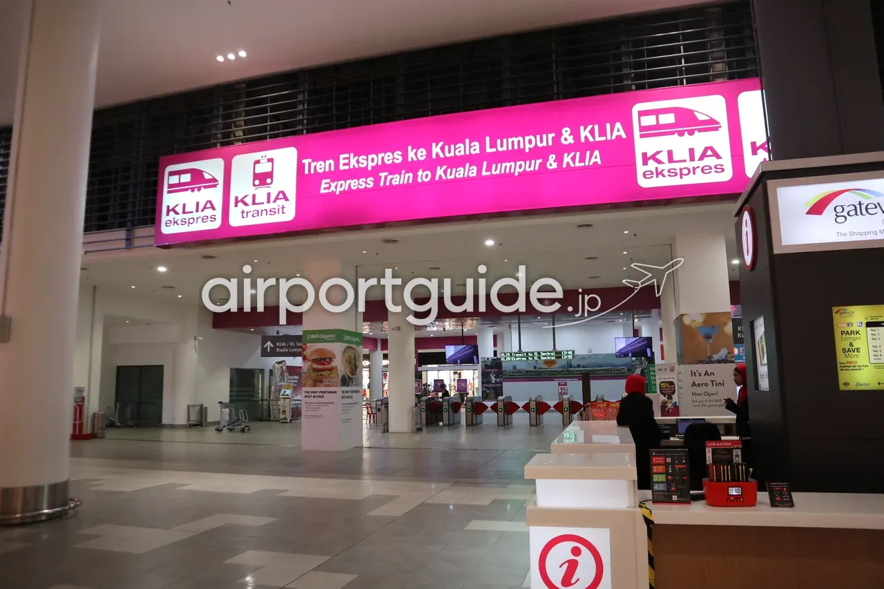 KLIAエクスプレス／KLIAトランジットの駅入口。ピンクの大きなサイン「Express Train to Kuala Lumpur & KLIA」と自動改札、右手にgateway@klia2の案内カウンター。