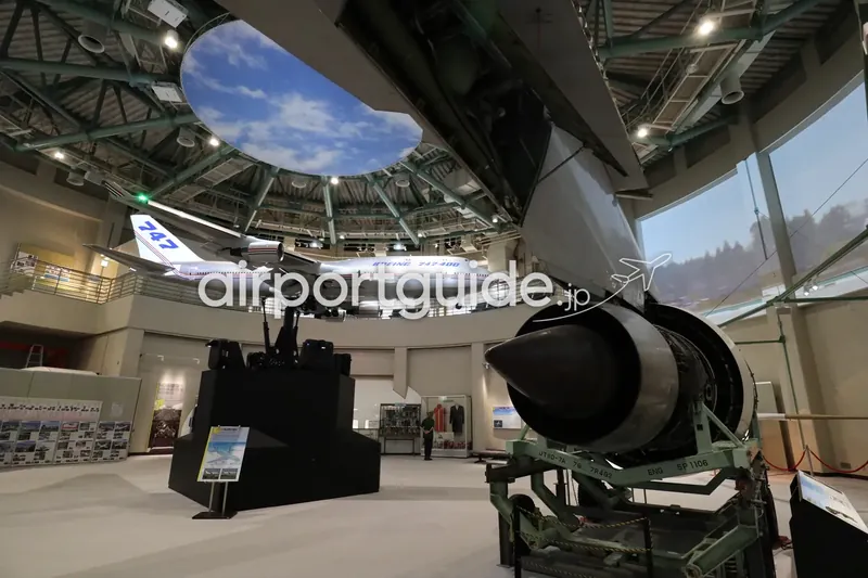 航空科学博物館の吹抜けドーム展示室。天井に747-400模型、手前にジェットエンジン実物が展示されている。
