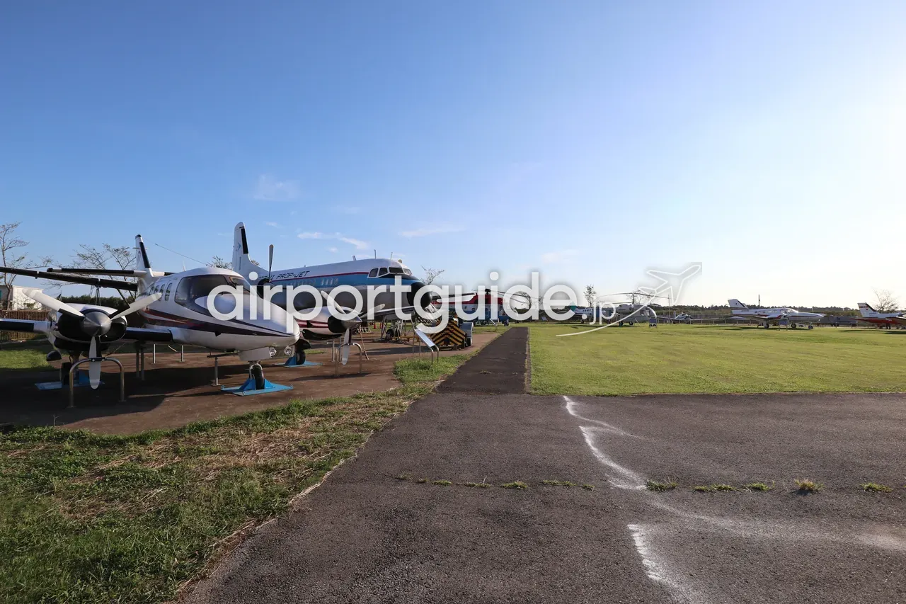 航空科学博物館の屋外機体展示場を地上から見た全景。退役したプロペラ機やヘリコプター、小型機が芝生に並ぶ。