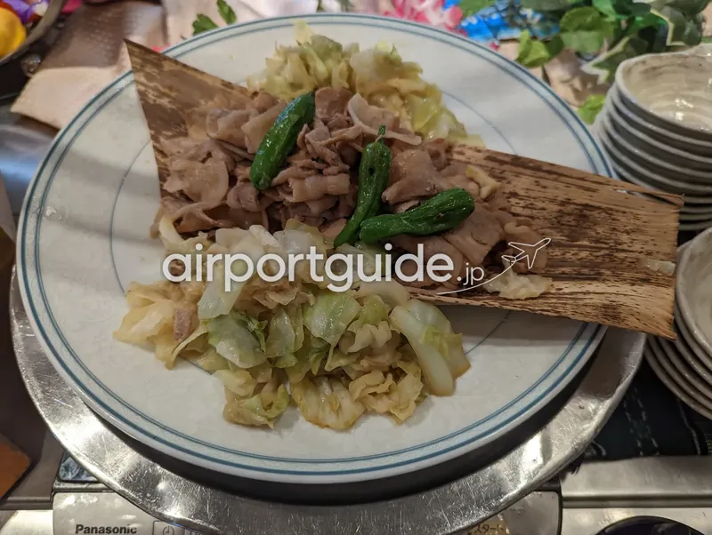 皿に盛られた豚肉とキャベツの炒め物。ししとうを添えた一皿。