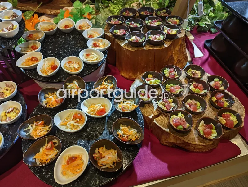 前菜コーナー。なますやマグロとアボカドのポキ風の小鉢が石皿と木の台に並ぶ。