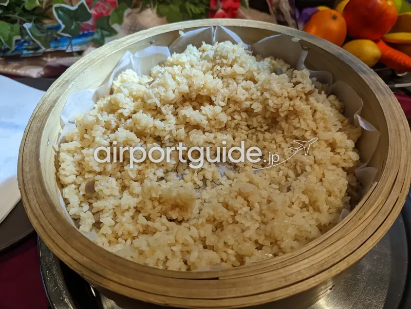 竹せいろで蒸した炊き込みご飯の寄り。薄い醤油色のご飯がクッキングシートを敷いたせいろに盛られる。