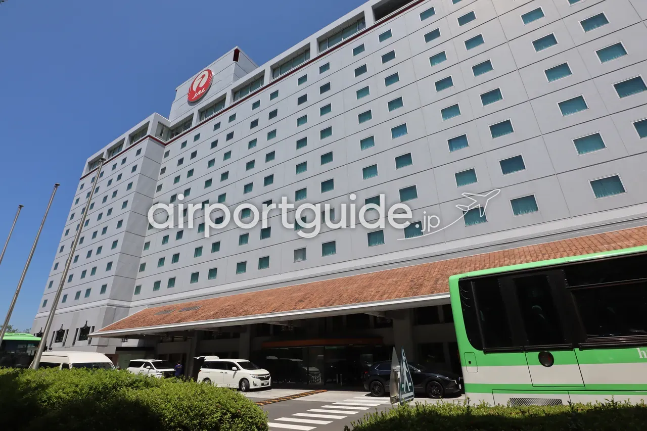 ホテル日航成田の外観。屋上にJALの鶴丸ロゴを掲げた高層の建物と車寄せ、緑の送迎バスが写る。
