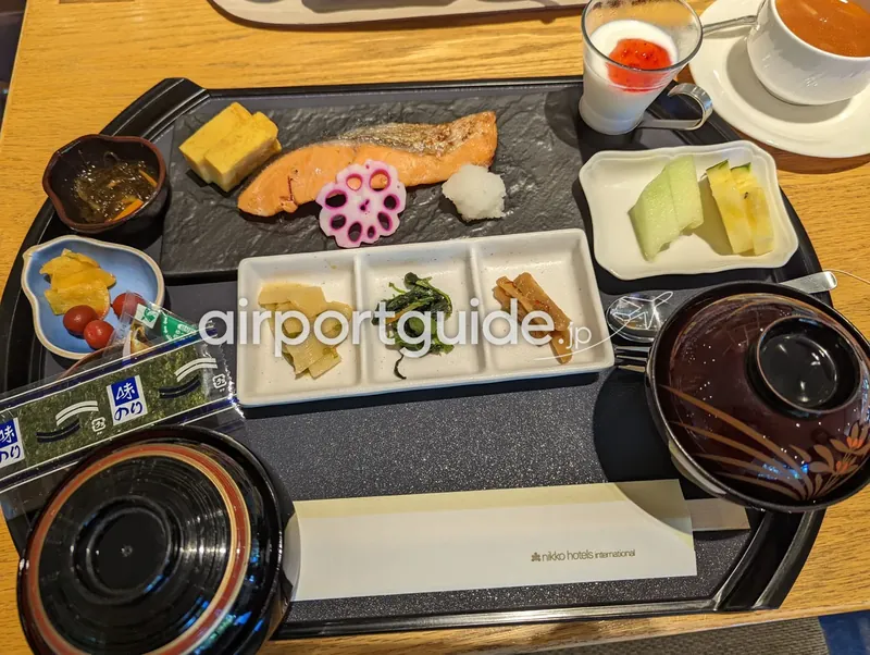 和朝食膳。焼き鮭・卵焼き・小鉢・味付海苔・味噌汁・ご飯。