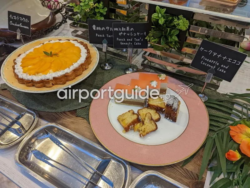 ケーキ類。黄桃のタルトと数種のカットケーキが並ぶ。