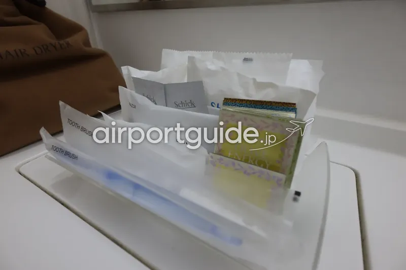 ホテル洗面台のアメニティ一式（歯ブラシ・カミソリ・入浴剤など）のクローズアップ。