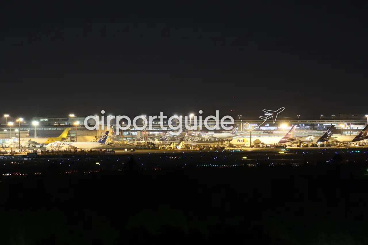 ホテルマイステイズプレミア成田の客室から望遠で捉えた、夜の成田空港のエプロン。ライトに照らされた貨物機が並ぶ。
