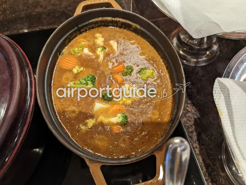 鋳物鍋の野菜カレー（蓋を開けた状態）。ブロッコリーや人参が浮かぶ。