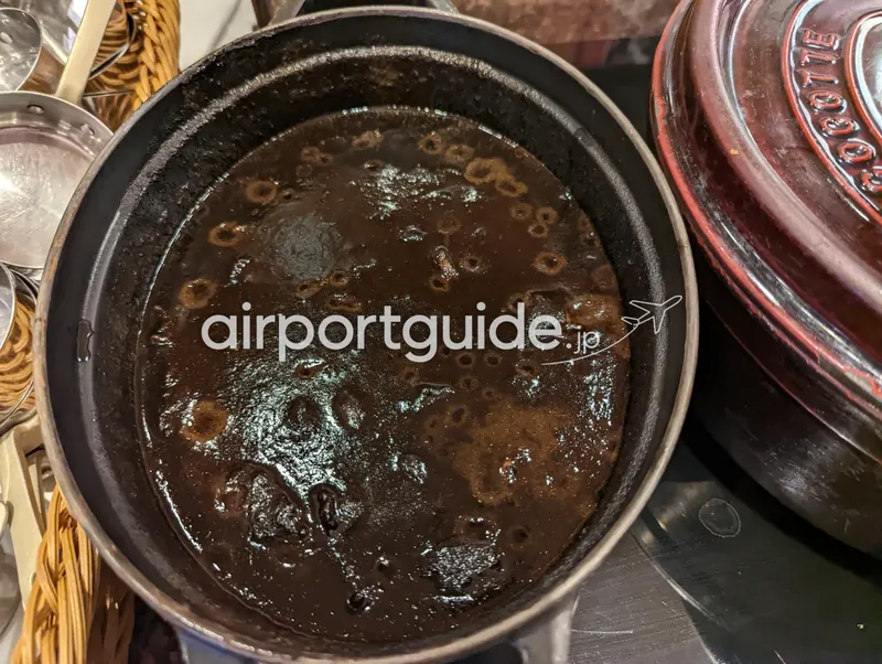 鋳物鍋の黒っぽいカレー（マサラ黒カレーと見られる）。
