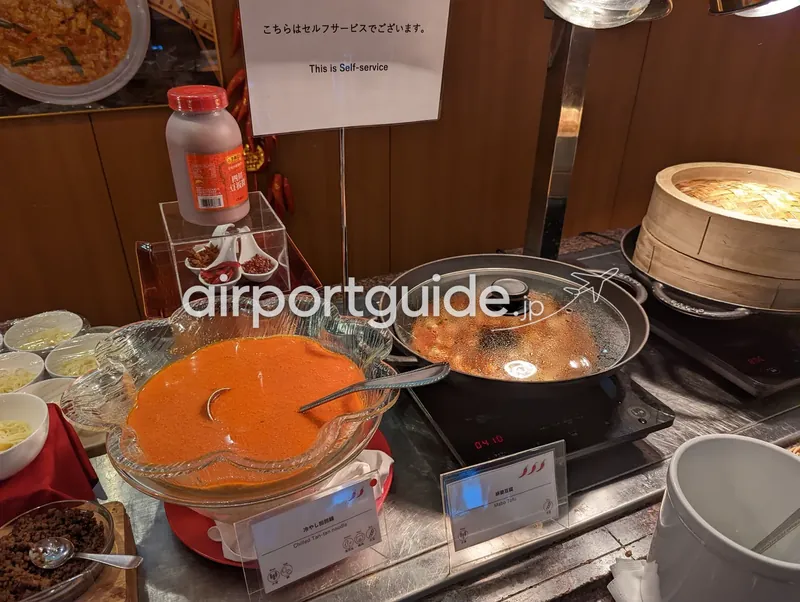 セルフサービスの中華ビュッフェ台。冷やし担担麺のスープと麻婆豆腐の鍋、蒸籠が並ぶ。