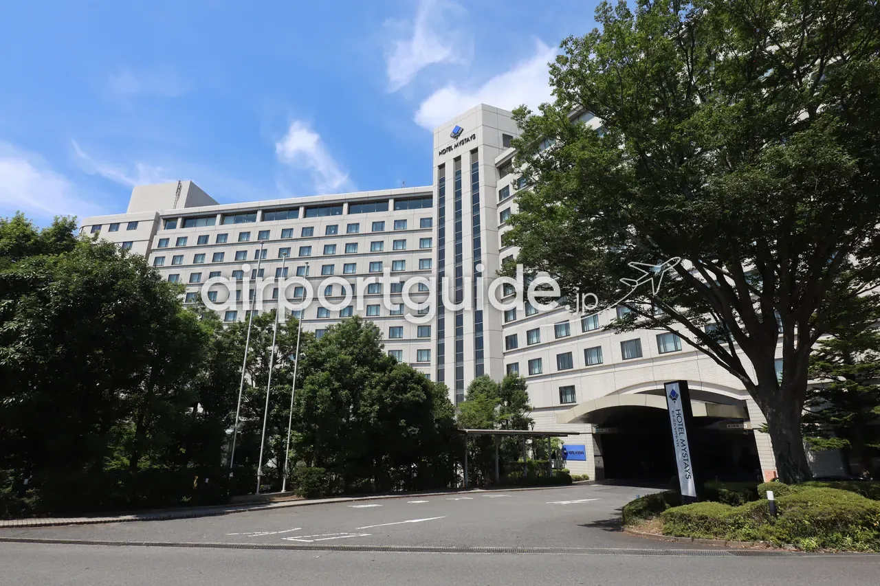 マイステイズプレミア成田の全景外観。車寄せのある正面エントランスと白い高層棟。