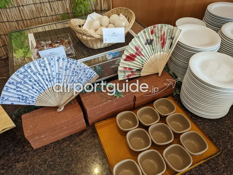 ホテルの和食ビュッフェの温泉卵コーナー。卵の入った籠、専用タレ、和風の飾り扇子。