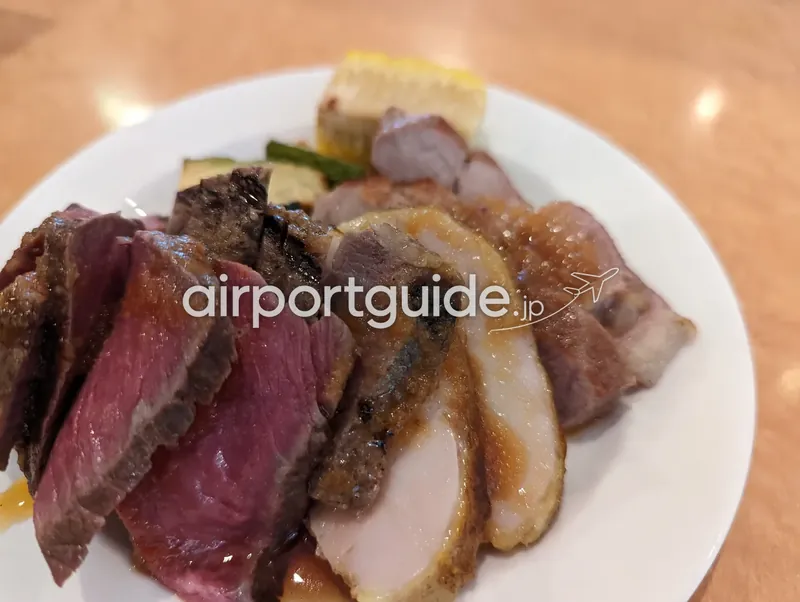 白い皿に盛り付けられたグリルした牛肉・豚肉・鶏肉とグリル野菜のクローズアップ。