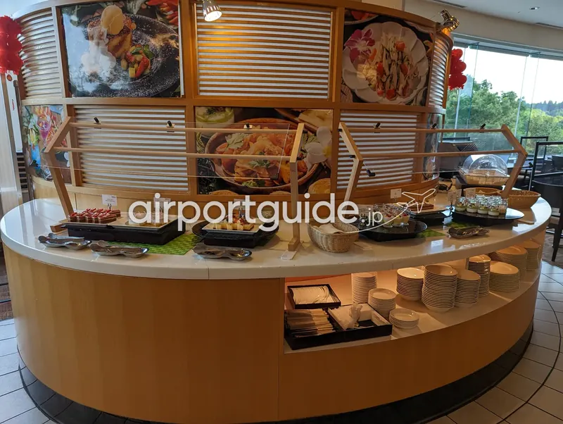 デザート＆パンコーナー全景。円形の木目カウンターに料理写真パネルとケーキ類。