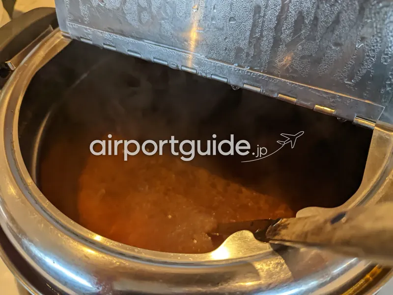 温かいカレー／スープ。湯気の立つオレンジ色のカレーとレードル。