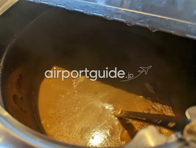 温かいカレー。保温鍋の中の茶色いカレーとレードル。