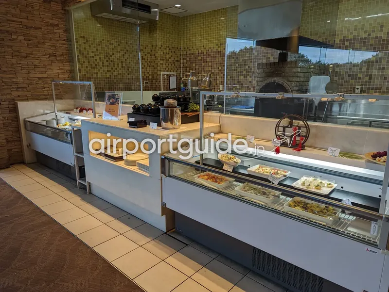 冷菜ケースと麺コーナー全景。ガラスの冷蔵ショーケースに惣菜が並び、奥に石窯。