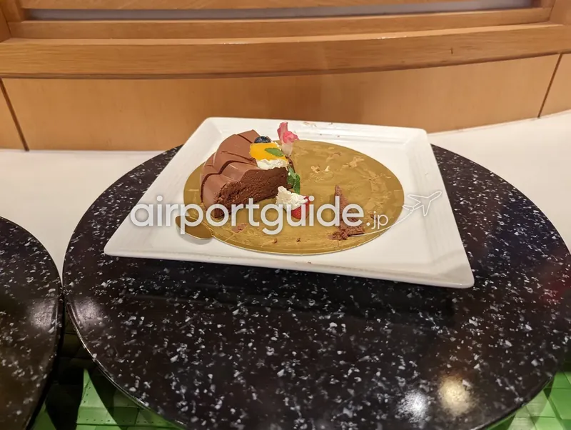 マンゴームースケーキ。黄色いムースにフルーツを飾ったケーキ（半分）。