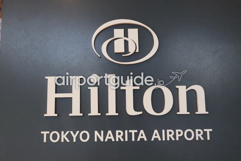 「Hilton TOKYO NARITA AIRPORT」のロゴサイン。濃紺の壁に白抜きのヒルトンロゴと文字。