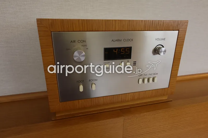 ホテル客室の枕元コントロールパネル。空調・アラームクロック・音量・ラジオの操作部。