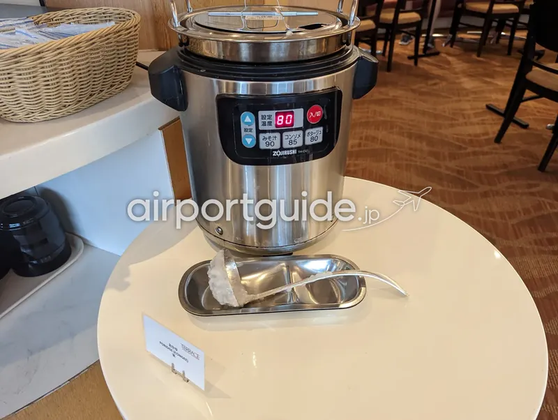お粥コーナー。ZOJIRUSHIの保温器と杓子を置いた丸テーブル。