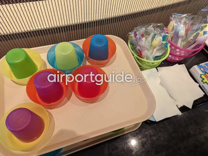 子ども用食器コーナー。カラフルなプラスチックのコップと子ども用カトラリー。