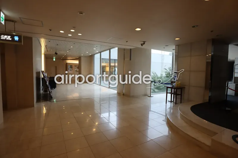 ホテルのロビー/通路。「化粧室 REST ROOM」案内のある明るい大理石の空間。