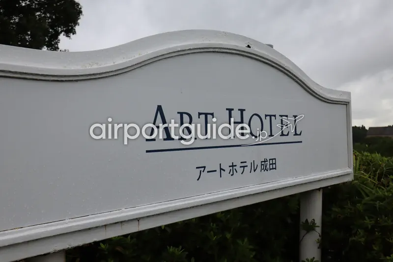 ホテルの案内看板。「ART HOTEL / アートホテル成田」と記された白い立て看板。