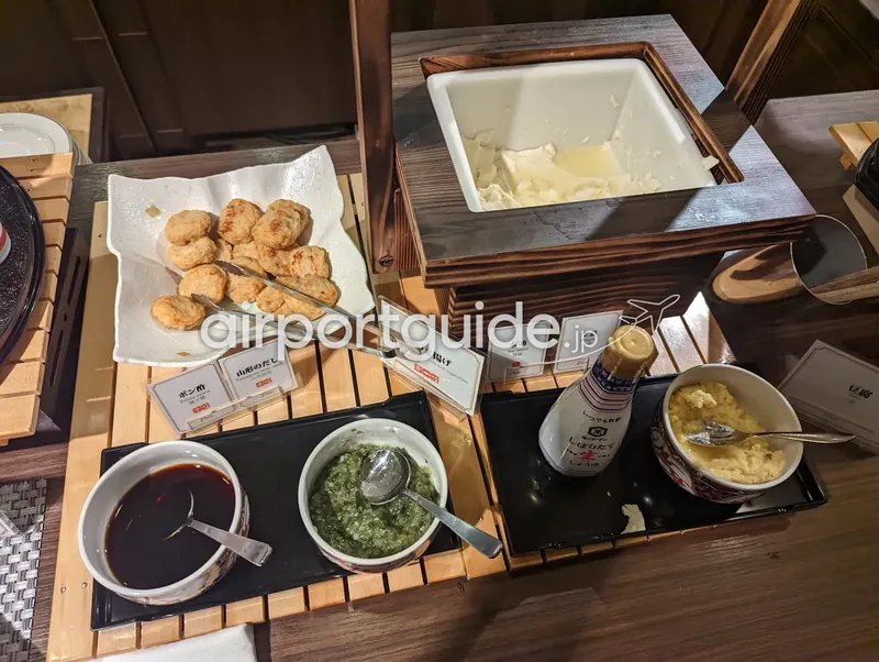 ホテル和朝食ビュッフェの豆腐・さつま揚げコーナー。冷奴用の豆腐と揚げ物、薬味や調味料が並ぶ。
