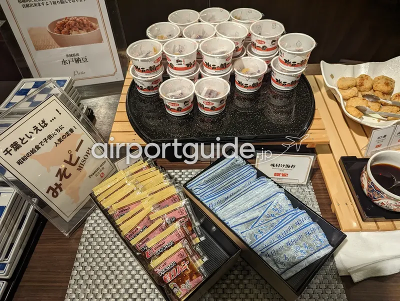 ホテル和朝食ビュッフェの納豆コーナー。茨城県産『水戸の朝』納豆のカップが並び、味付け海苔やみそピーが添えられる。